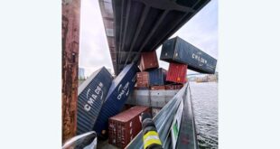 containers dangling from cargo ship stuck under railway bridge